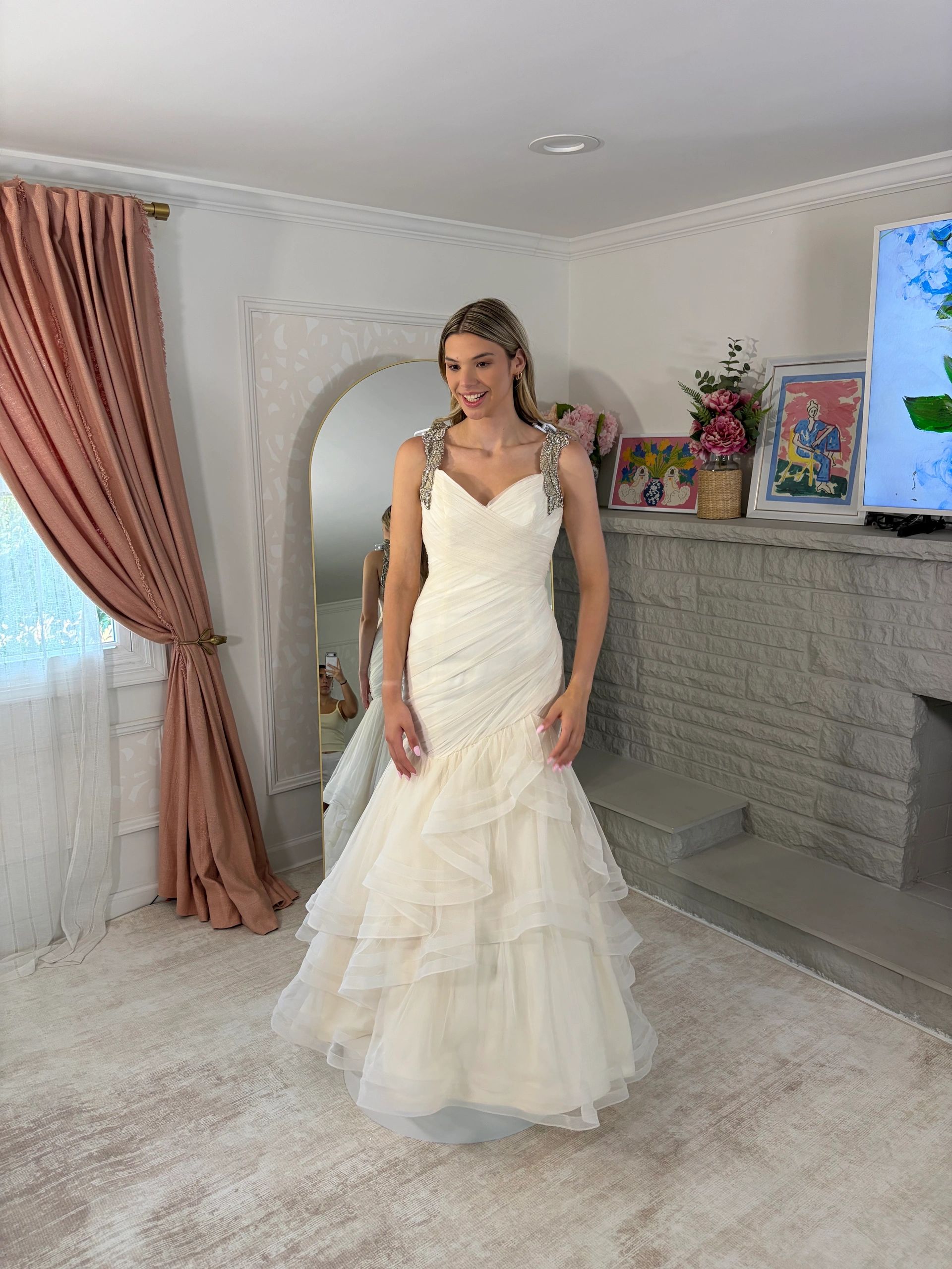 Woman in a stylish white layered gown smiling indoors.
