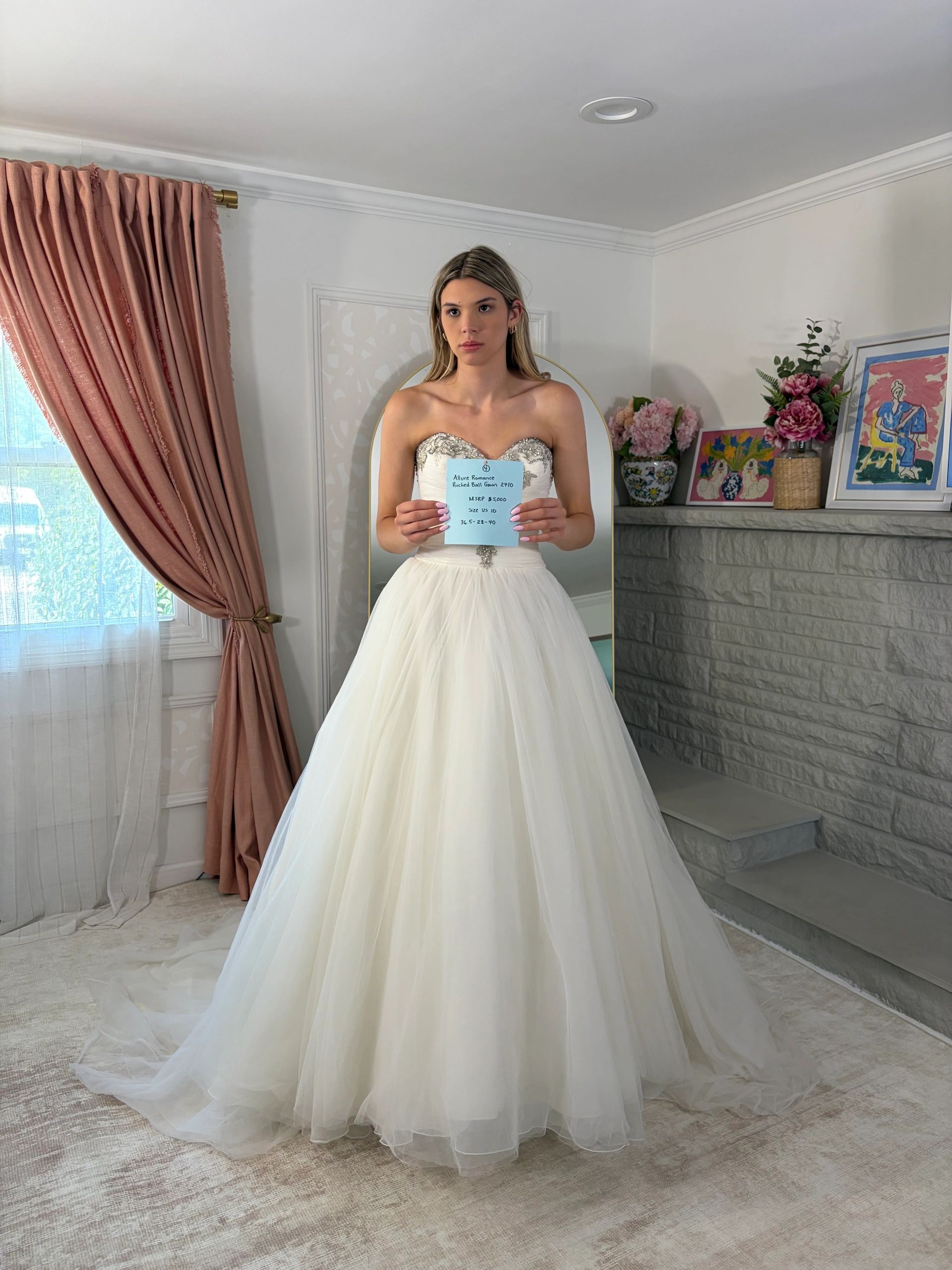 Bride in elegant wedding dress holding a note indoors.