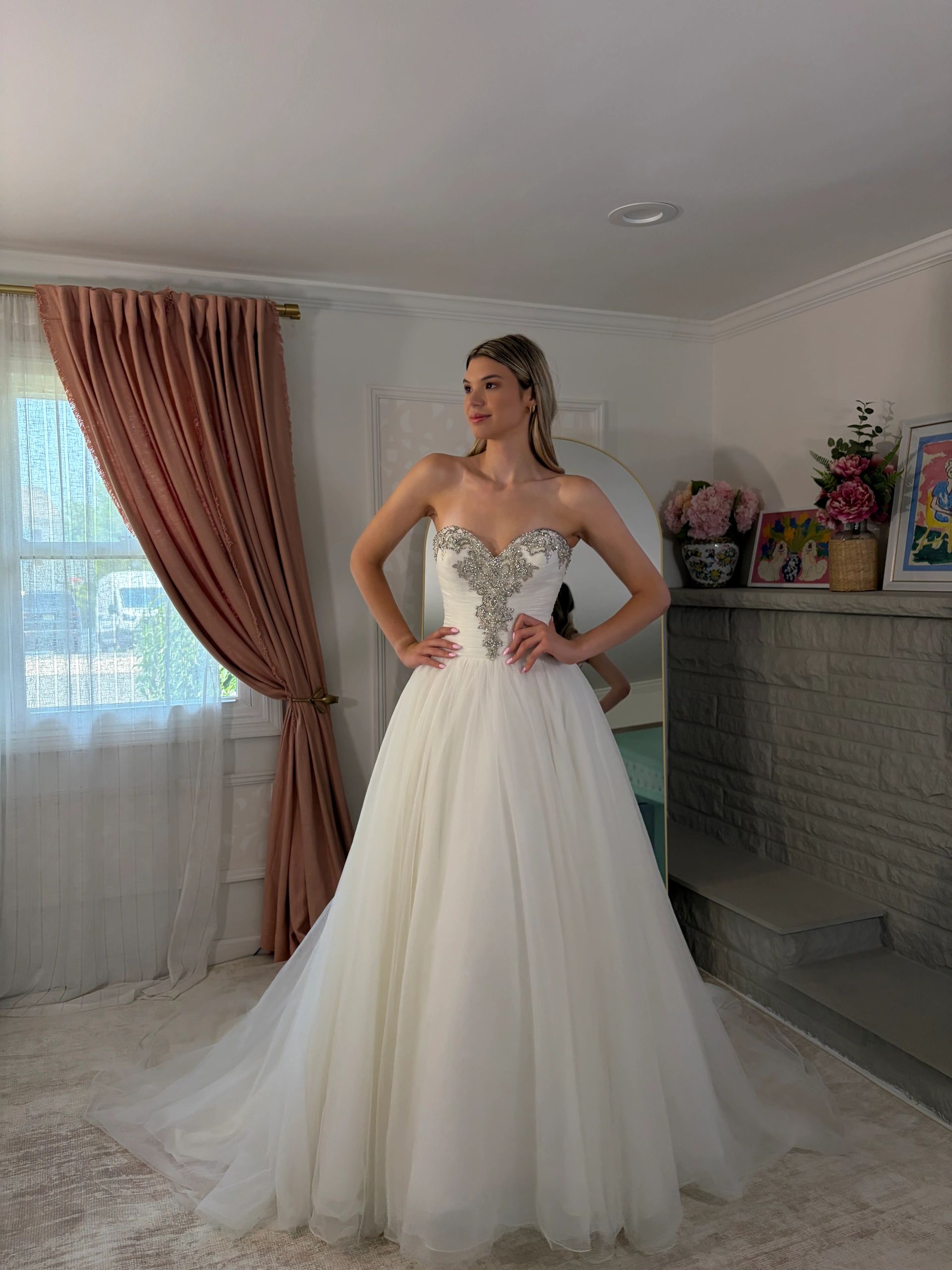 Woman modeling an elegant white wedding dress indoors.