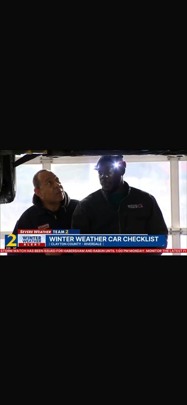 Two men under a vehicle discussing winter weather car checklist.