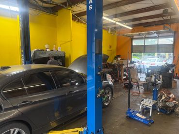 Busy auto repair shop with cars and tools scattered around.
