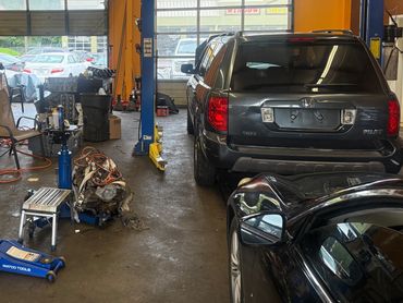 Inside a busy auto repair garage with vehicles and tools scattered around.
