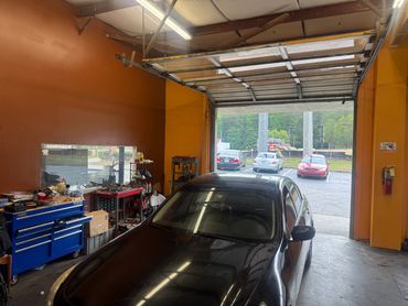 Inside view of a car repair garage with a black car and tools.