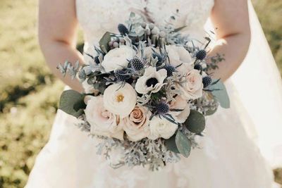 Bride holding her round bouquet with grey, white, blush, and blue flowers. 