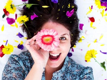 Woman surrounded by spring flowers ready for the Spring Glow Up Workshop