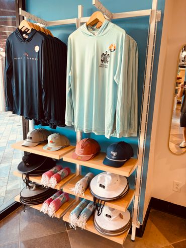 Display of Maui-themed clothing and accessories including hats and hoodies.