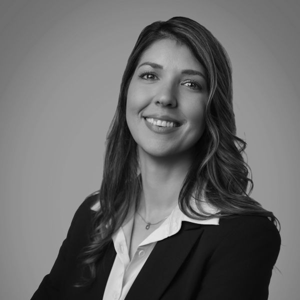 Professional woman in business attire smiling confidently in black and white.