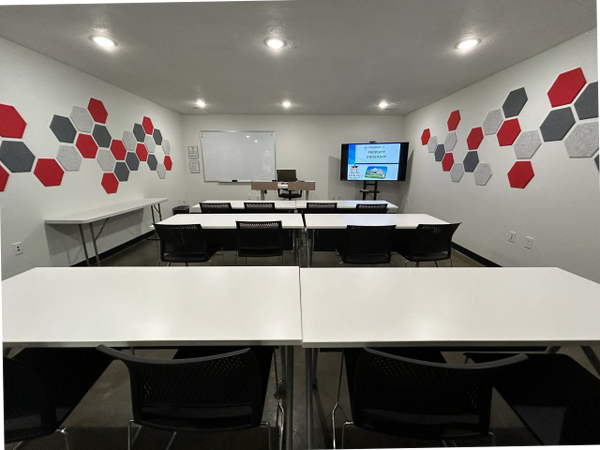 Modern Real Estate classroom with white desks and hexagonal wall decorations in red, gray, and black. Seated Classroom