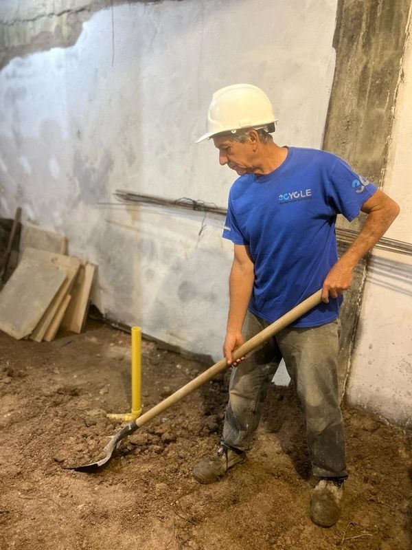 Construction worker with a shovel preparing ground inside a building.