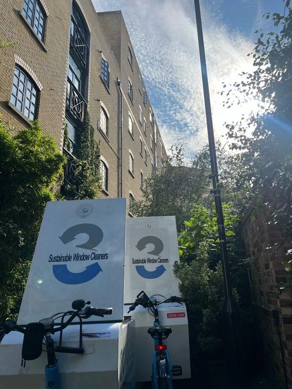 Bicycles parked near sustainable window cleaning equipment beside a brick building.