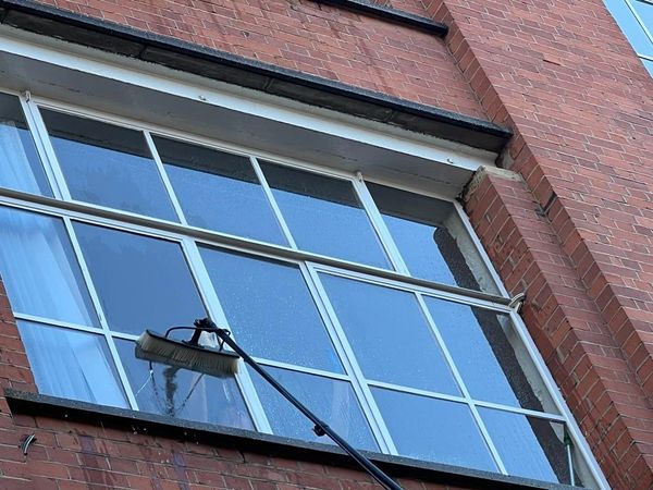 A brush cleaning a large glass window on a brick building.