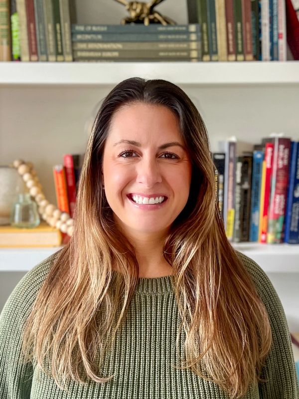 Smiling woman with long hair in front of a bookshelf.