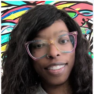 Smiling person wearing multicolored glasses with curly hair in front of a vibrant mural.