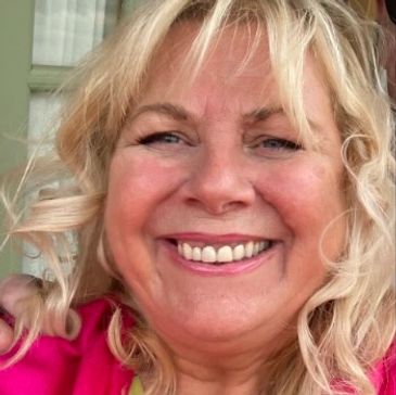 Smiling woman with blonde hair wearing a pink top.
