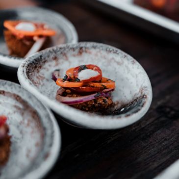 Appetizer with roasted vegetables on a speckled ceramic plate.