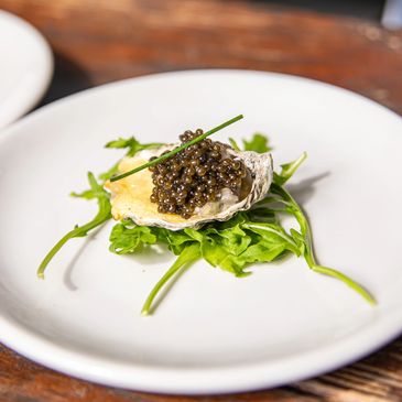 Gourmet oyster topped with caviar on greens.