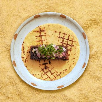 Gourmet taco with grilled meat and fresh toppings on a patterned tortilla.