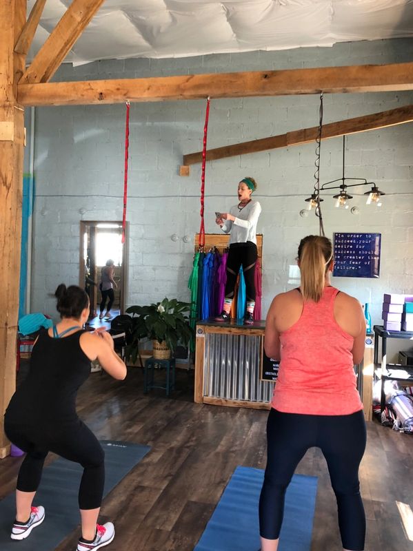 Two women exercising in a studio with an instructor on a platform.