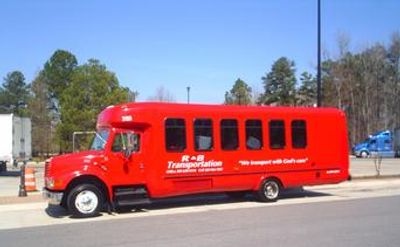 Red transportation shuttle bus parked on the street.