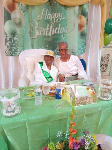 Elderly woman celebrates 104th birthday with family at decorated party.