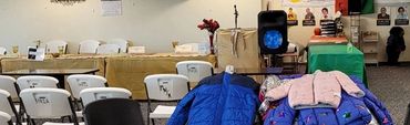 Community coat drive event with chairs and coats displayed indoors.
