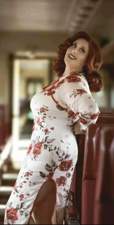 Woman in floral dress posing inside a train.