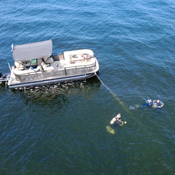 Pontoon boat with two divers in the water.