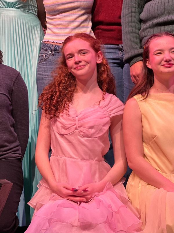 Young woman in a pink dress smiling.