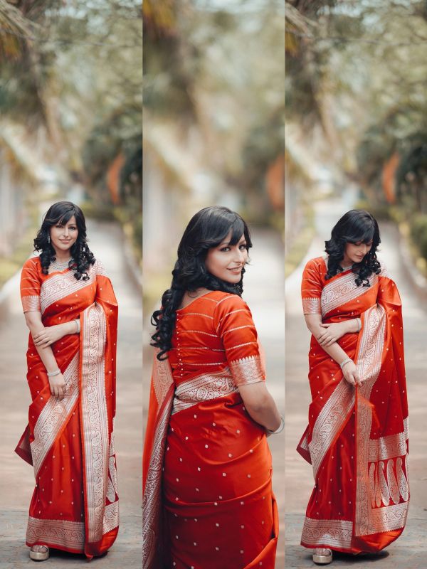 Woman elegantly posing in a red saree with intricate white designs.