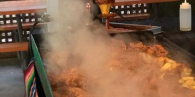 Steaming grilled meat cooking on a large outdoor grill.