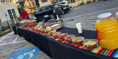 Outdoor buffet table with various dips and a large drink dispenser.