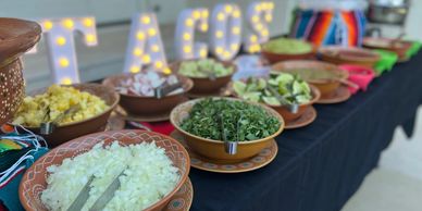 Mexican taco toppings arranged in bowls on a black tablecloth.