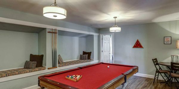 Cozy game room with a red pool table and cushioned seating nook.