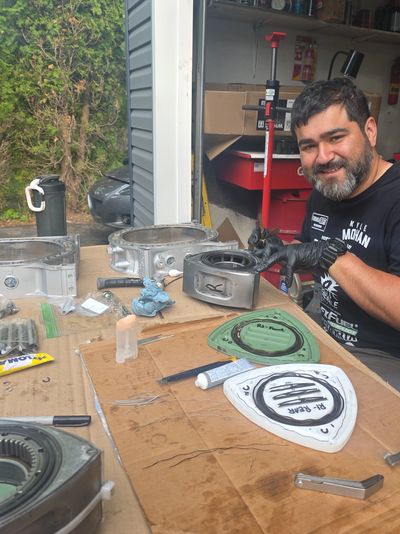 Man working on engine parts outdoors.