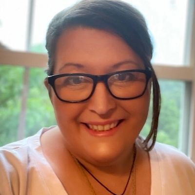 Smiling woman wearing glasses in front of a window.