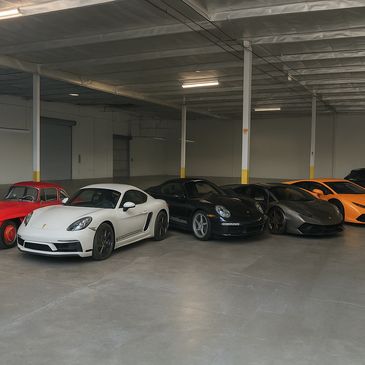 A lineup of classic and modern sports cars in a spacious garage.