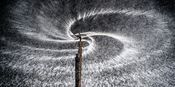 Water sprinkler creating a spiral pattern of water droplets.