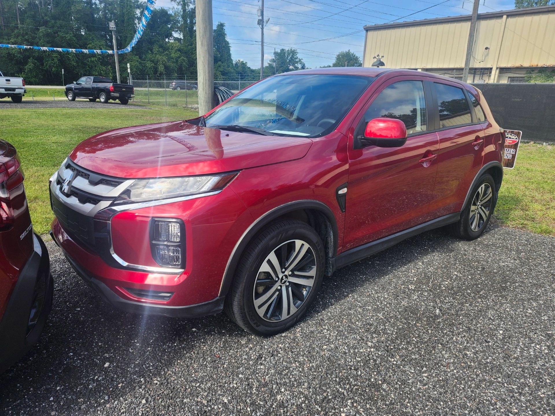 Red Mitsubishi SUV parked outdoors on a sunny day.