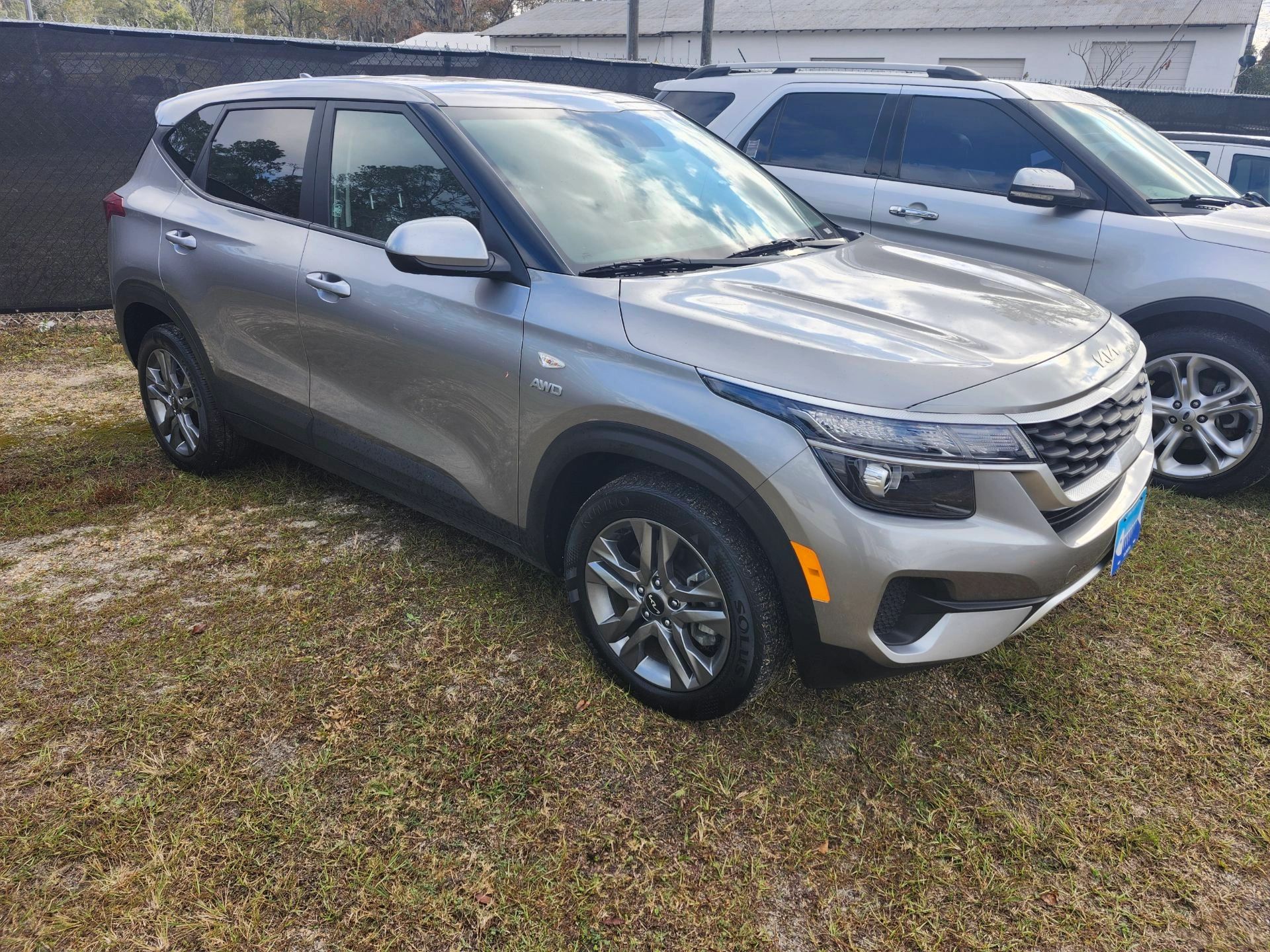 Silver Kia SUV parked on grass with AWD badge visible.