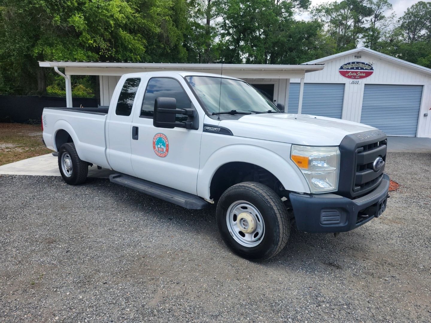 White Ford F-250 pickup truck parked outside a building with blue garage doors.