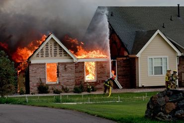 Firefighters battling a house fire with flames engulfing the building.