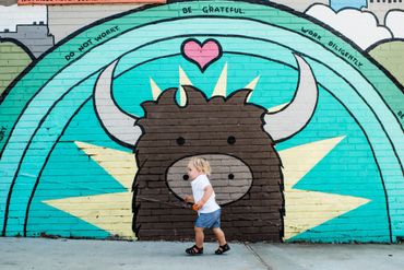 A boy who has Vein of Galen Malformation (VOGM, VGM) walking I front of a mural of a bull.