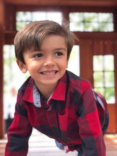 A Vein of galen malformation (VOGM) boy in plaid shirt smiling.