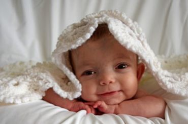 Vein of Galen Malformation (VOGM/VGM) baby girl peaking out from under a blanket.