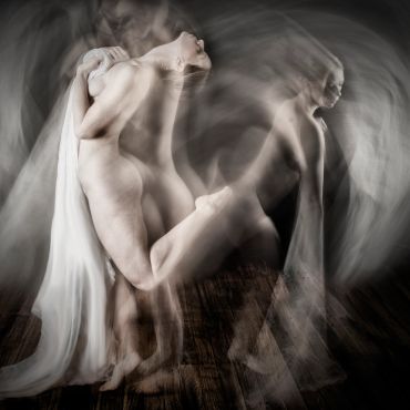 Artistic nude figure captured with motion blur and draped fabric.