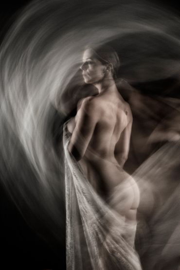 Artistic nude portrait with motion blur effect and flowing fabric.