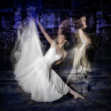Ballerina captured in graceful motion with flowing white dress and blurred effects.