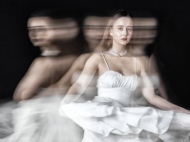 A woman in a white dress with a motion blur effect creating ghostly duplicates.