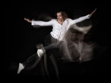 Man in white shirt and black pants captured mid-jump with motion blur.