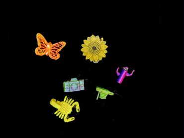Colorful embroidered patches of butterfly, sunflower, camera, scorpion, cactus, and gun on black background.